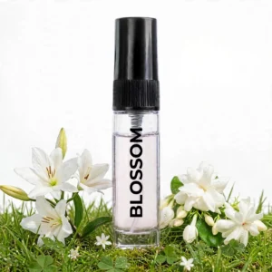 CocoBerry Blossom 5ml tester perfume bottle surrounded by white lilies, jasmine flowers, and fresh green grass.