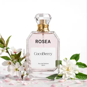 Rosea Eau de Parfum 50ml by CocoBerry in a clear glass bottle with a gold spray cap, surrounded by white floral blossoms on a white background – Everyday Perfume for Women