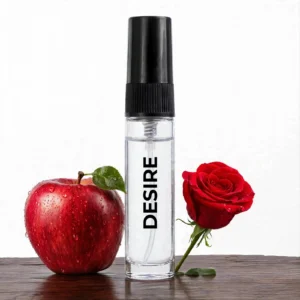 CocoBerry Desire 5ml tester perfume bottle displayed on wood alongside a crisp red apple and a fresh red rose.