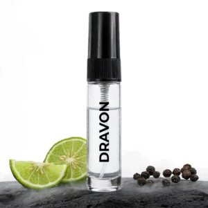 CocoBerry Dravon 5ml tester perfume bottle set against dark stone with sliced lime and whole black peppercorns.