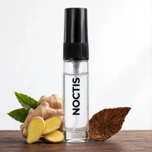 CocoBerry Noctis 5ml tester perfume bottle displayed on wood with fresh sliced ginger and a dried tobacco leaf.