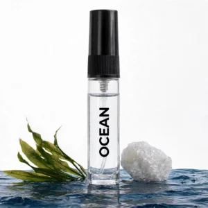 CocoBerry Ocean 5ml tester perfume bottle in rippling water with a sea salt crystal and green aquatic plant.