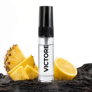 CocoBerry Victore 5ml tester perfume bottle displayed on dark textured wood with fresh sliced pineapple wedges and a half lemon.
